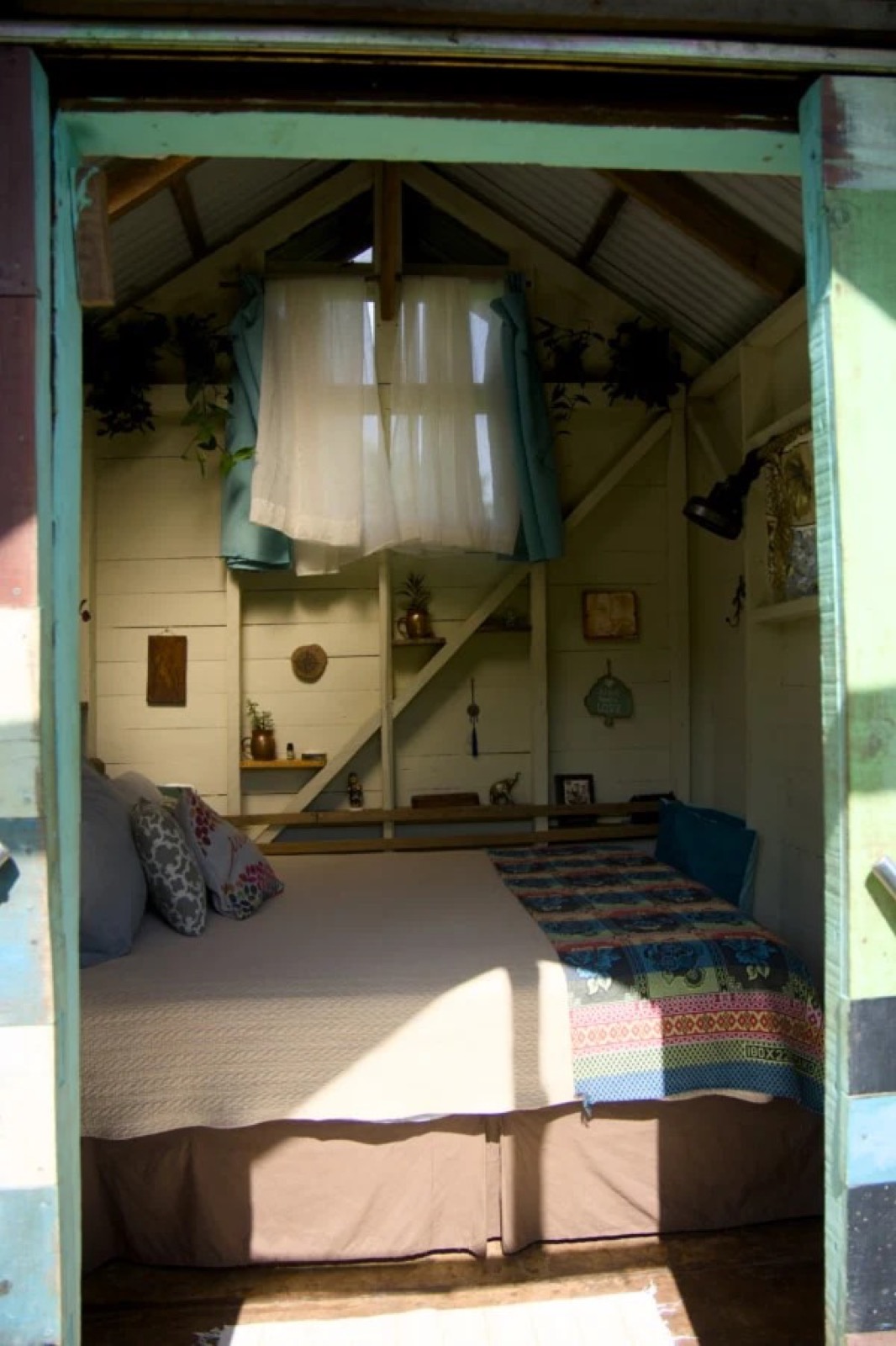 Cozy bedroom inside a tiny house with curtains and hardwood walls