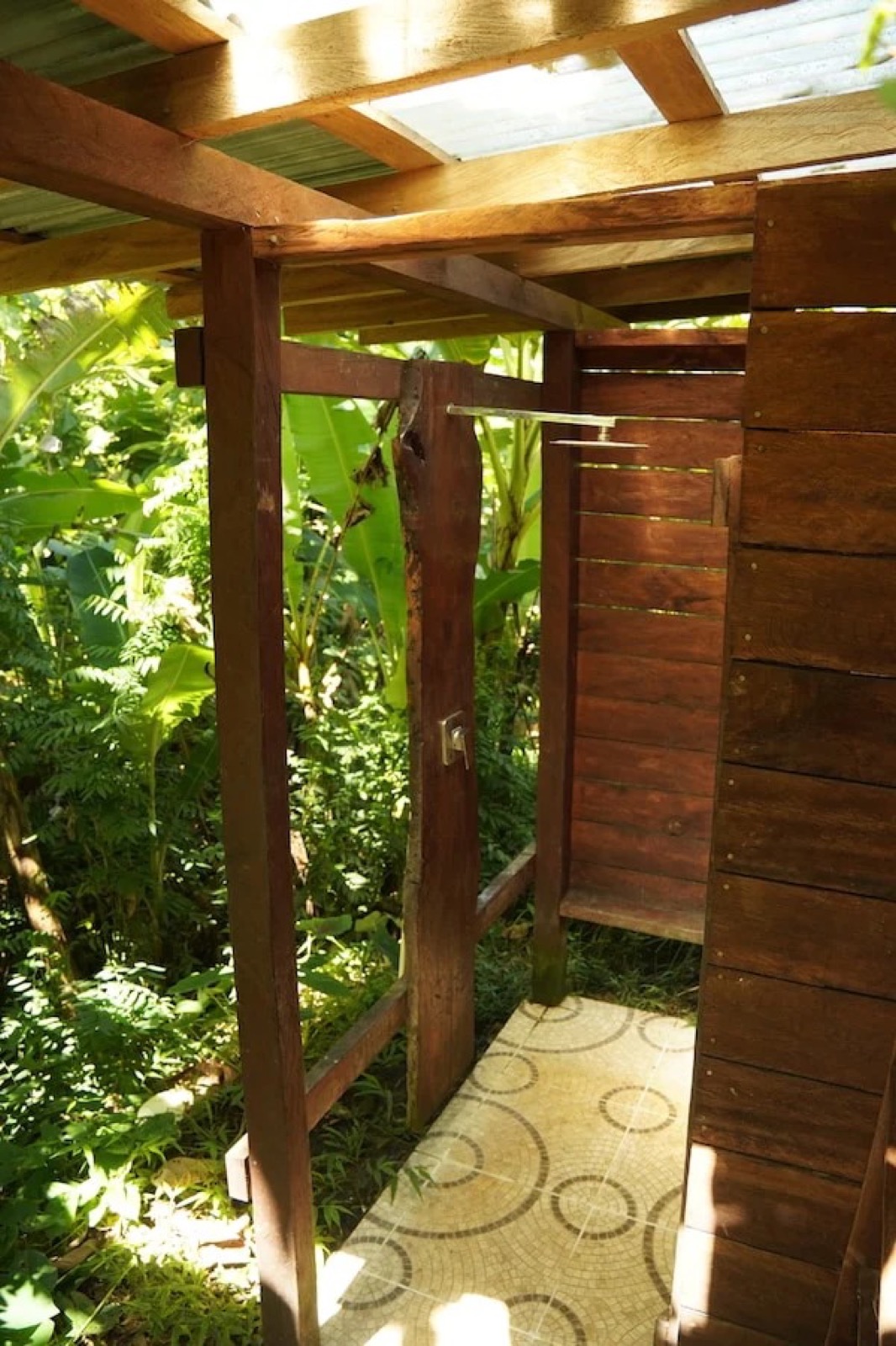 Open-air hardwood shower with a mosaic-tile floor