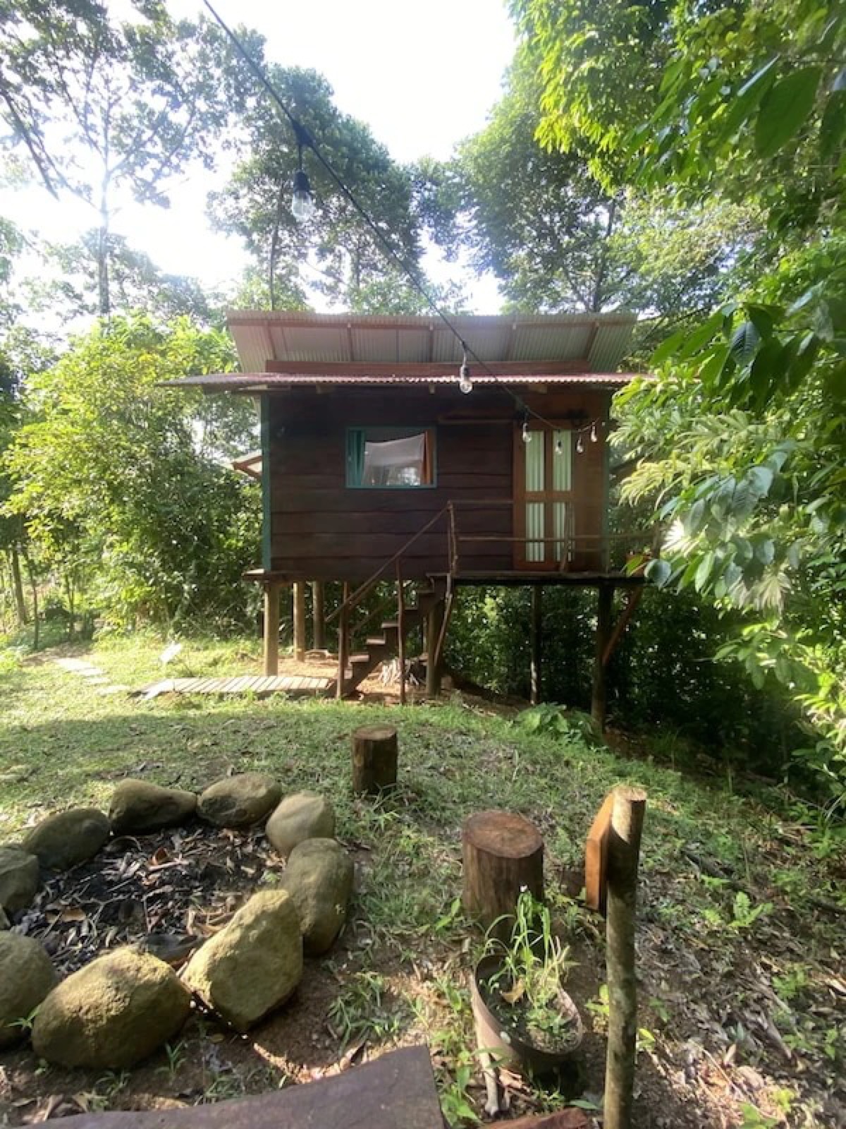 Stilted hardwood cabin with a fire pit in the jungle clearing