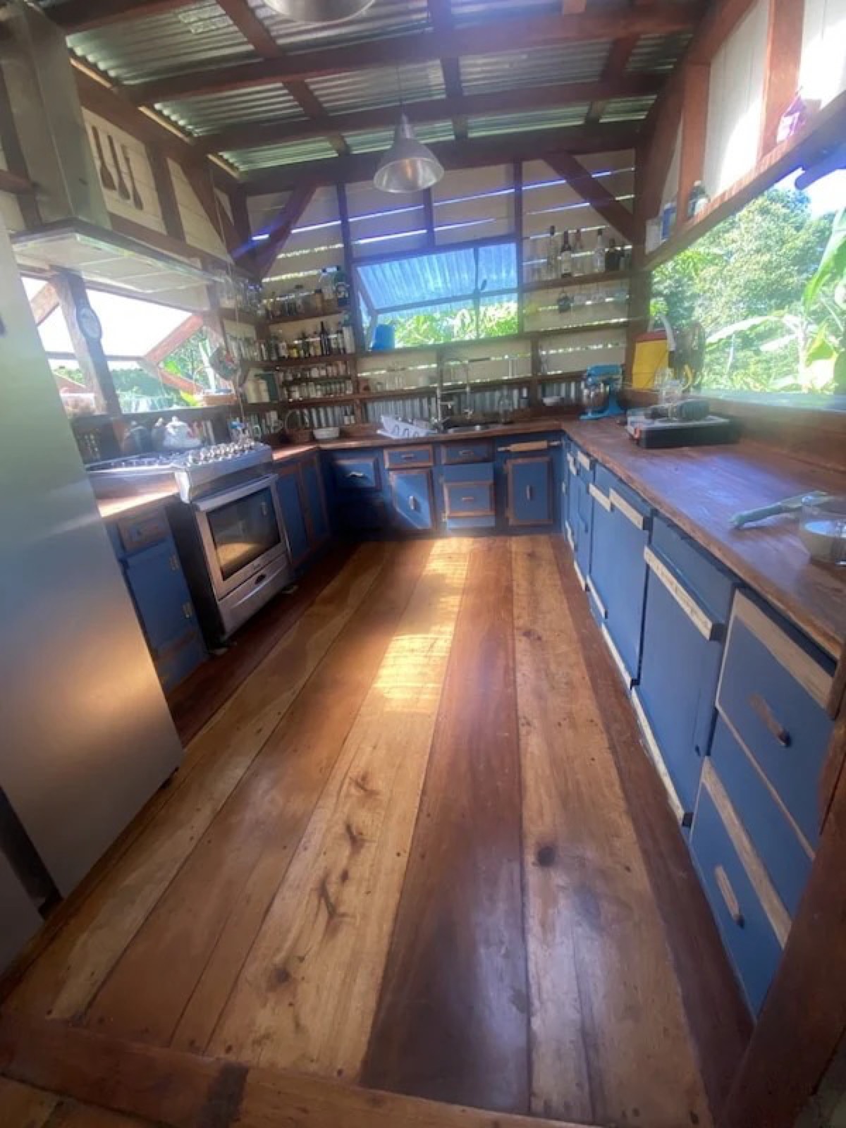 The open-plan kitchen with blue cabinetry, hardwood floors and jungle views