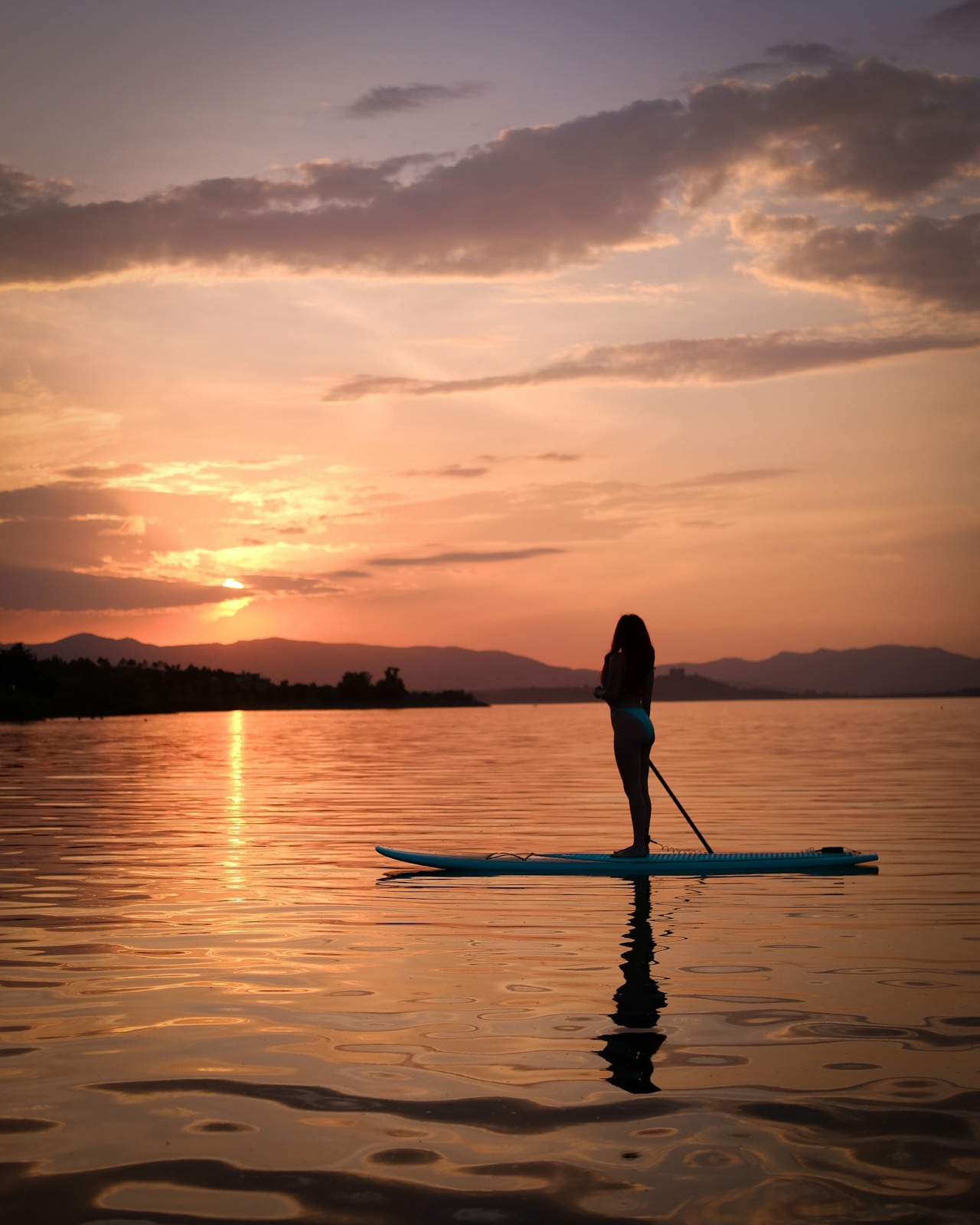 Stand-up paddleboarding on glassy water at sunset off the property